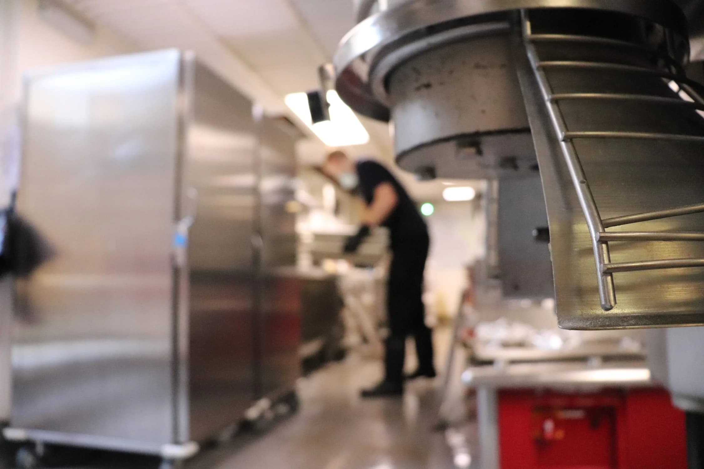 Bright technician cleaning a commercial kitchen surfaces to maintain hygiene and fire safety compliance.