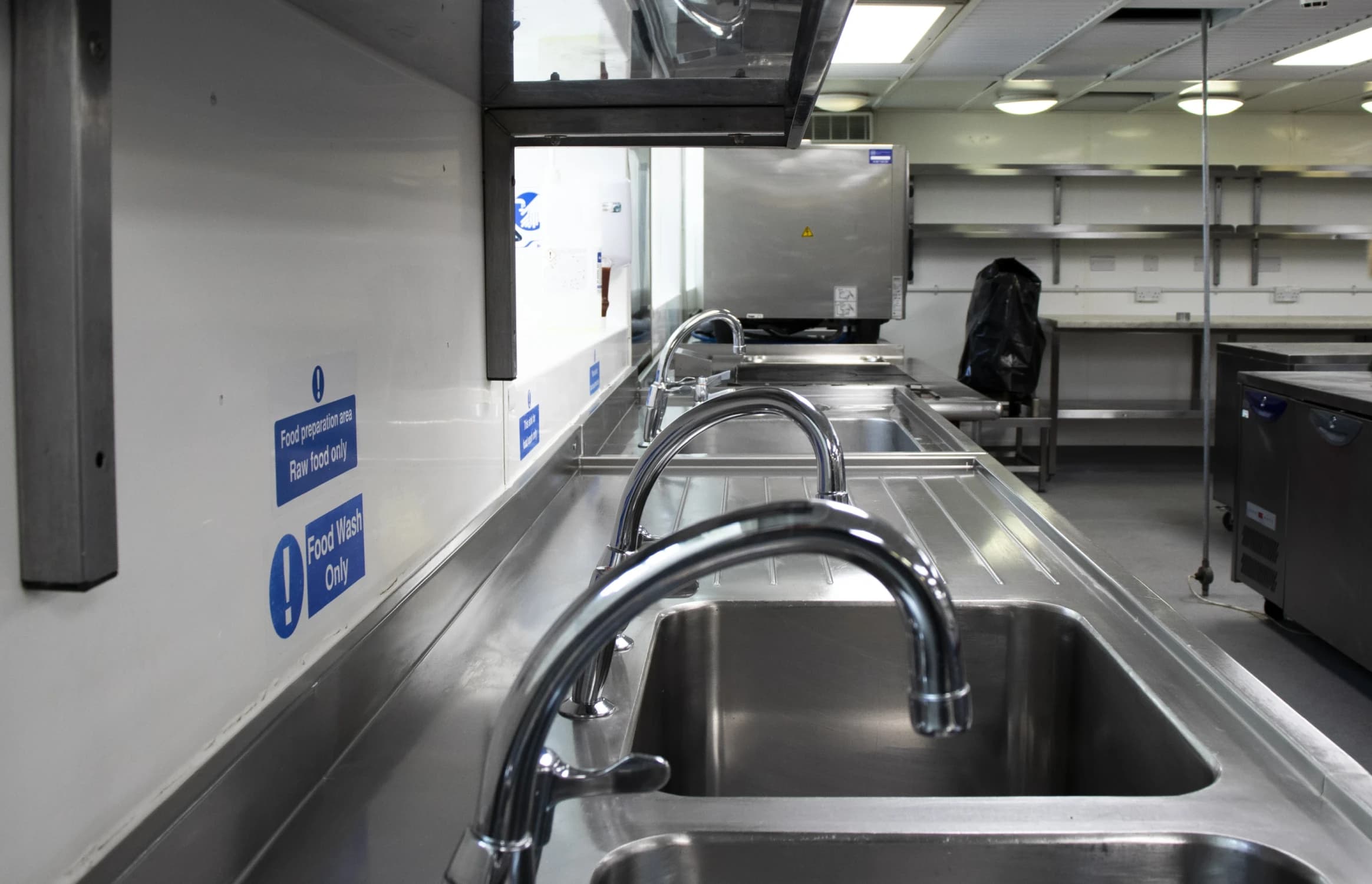 Sanitised commercial kitchen sinks and countertops demonstrating specialist hospitality cleaning.